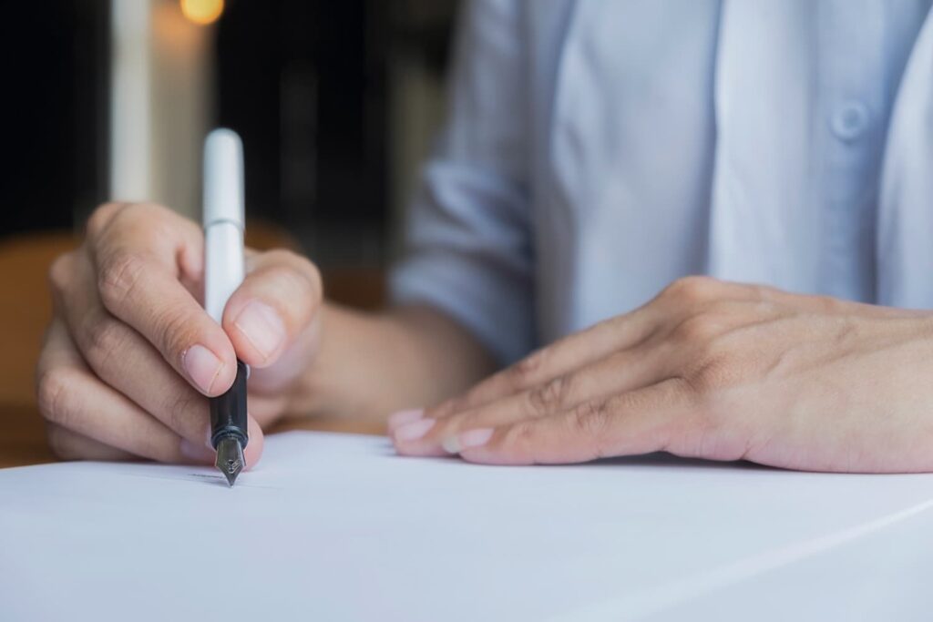 Tangan memegang kertas dengan tanda tangan, ilustrasi kasus palsukan tanda tangan.